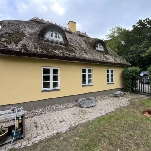 Facaderenovering af ældre hus i Tårnby med pudset facade og stråtag.