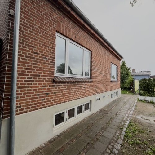 Facaderenovering på Amager med omfugning af murværk og pudset sokkel.