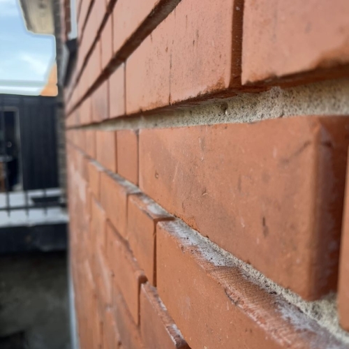 Close-up af facaderenovering på Amager med omfugning af murværk.