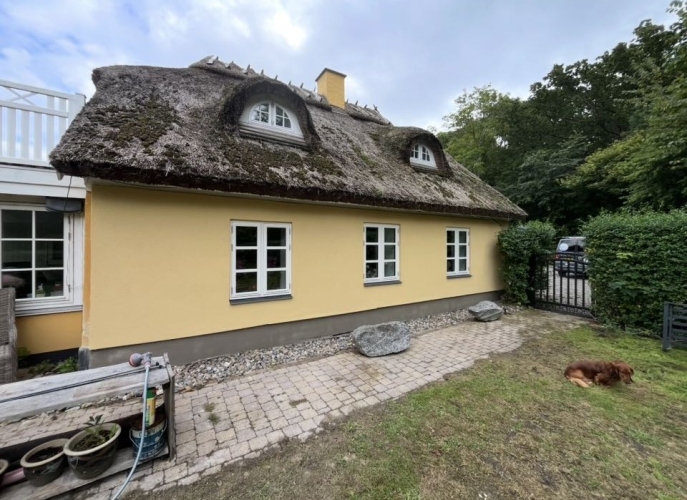 Facaderenovering af ældre hus i Tårnby med pudset facade og stråtag.