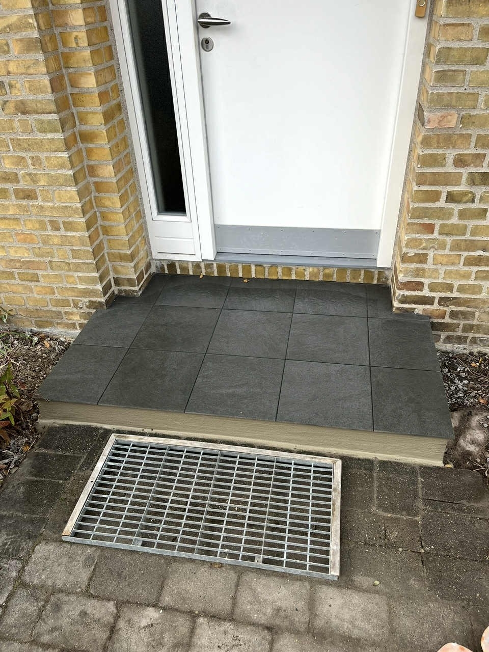 Flisearbejde ved indgang i Kastrup med nye flisetrin.